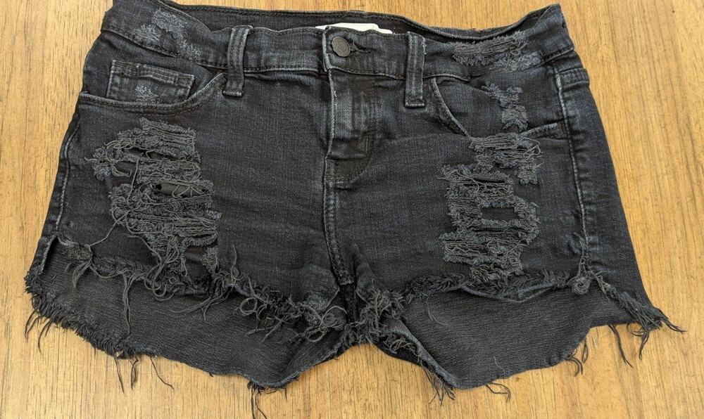 Day Trip denim shorts featuring a heavy black distressed wash and a frayed hem.